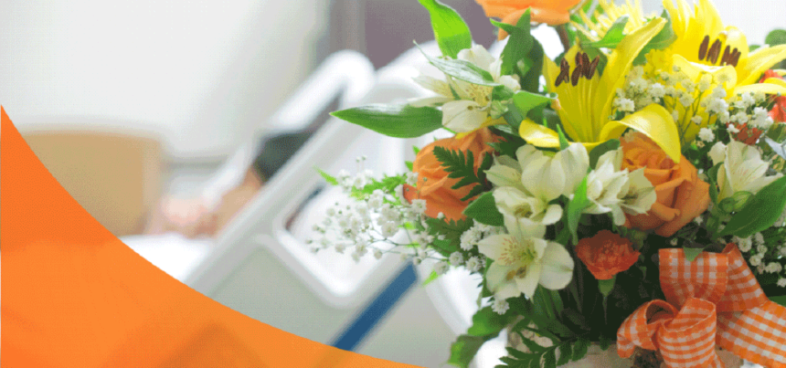 A bouquet of flowers and a patient lying in a hospital bed at the back