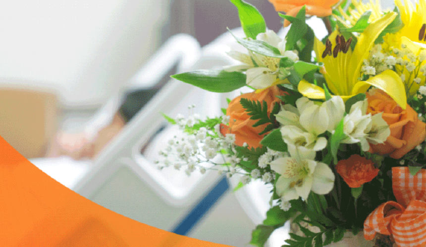 A bouquet of flowers and a patient lying in a hospital bed at the back