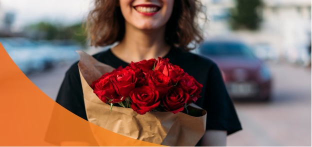 A Woman Happily Holding a Bouquet of Roses from Raphael's Gifts & Flowers